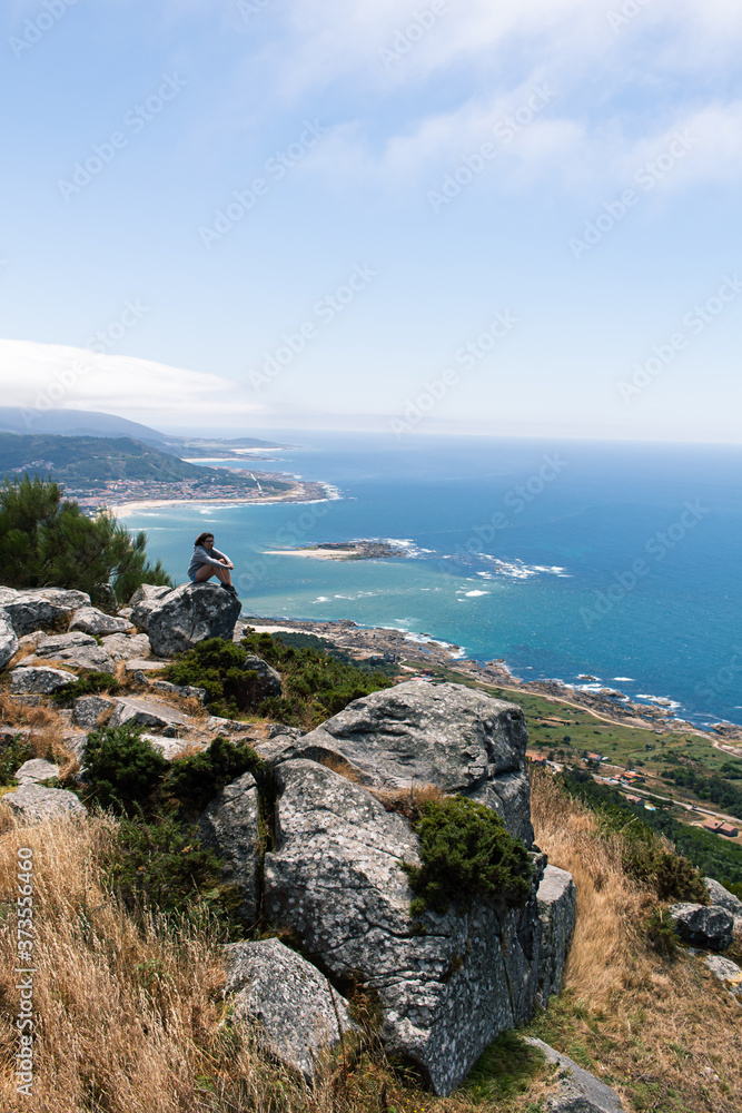 Attractive young female located on top of a rock witnessing the estuary of the Minho river in Galicia, north of Spain