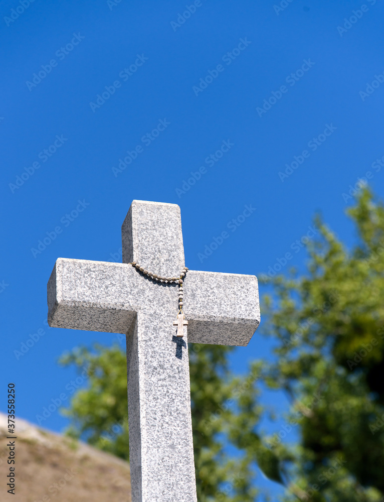 Christian granite cross on blue sky background with copy space