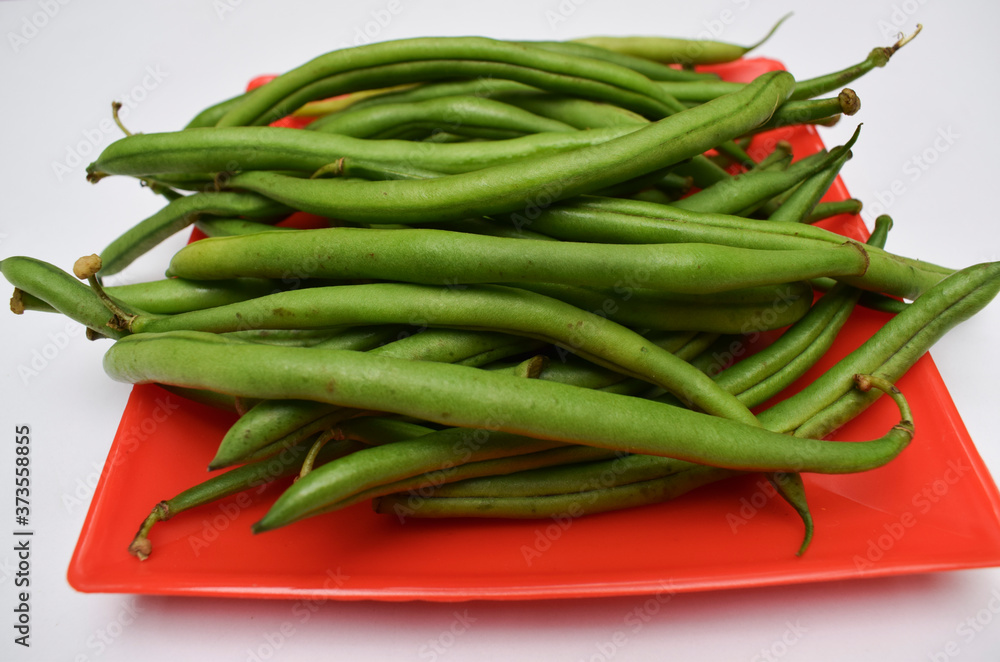 Fresh french beans Indian vegetables oon red plate with white background. Green beans bunch many veg fresh organic raw Fresh french beans Indian vegetables oon red plate with white background. Green beans bunch many veg fresh organic raw
