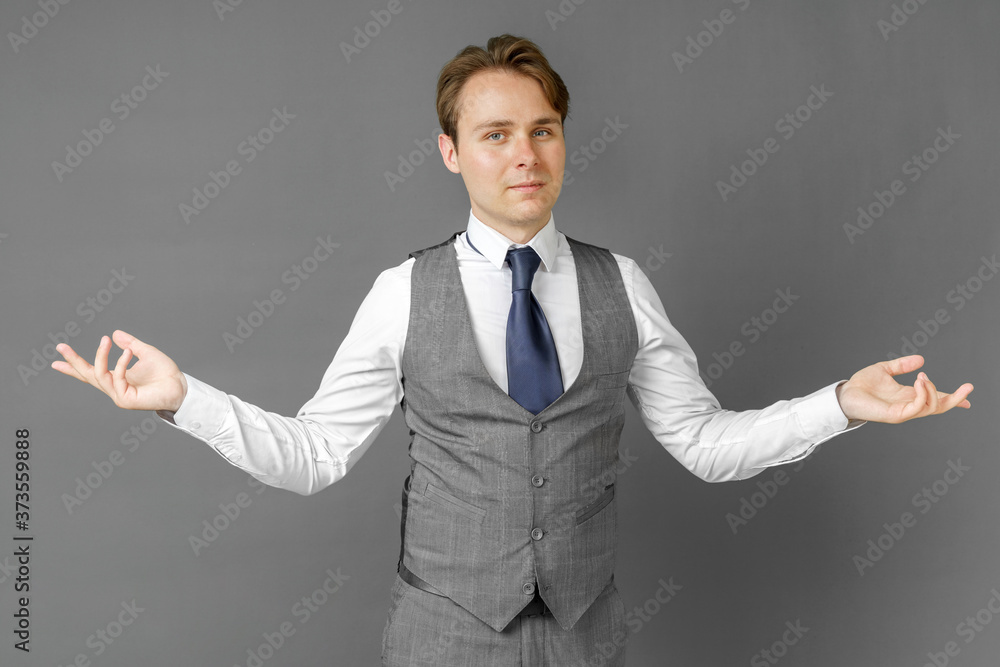 An emotional portrait of a businessman who shows with hand gestures in different directions. Gray background. An emotional portrait of a businessman who shows with hand gestures in different directions. Gray background.