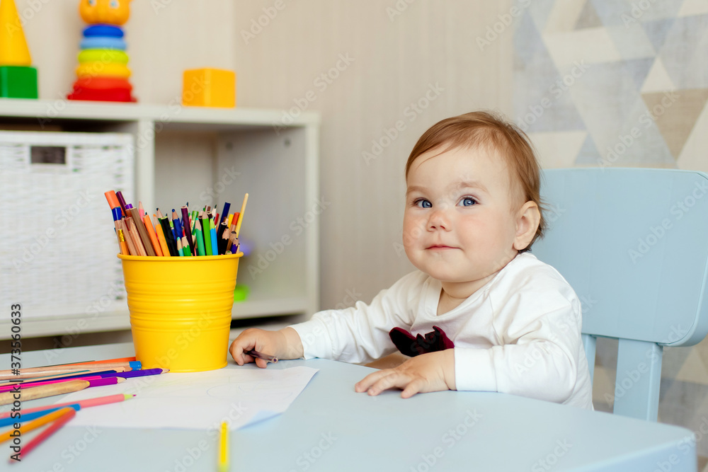 Happy little one year old girl draws with pencils at the table. Happy little one year old girl draws with pencils at the table.