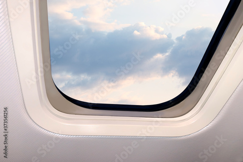 beautiful sky blue sky landscape with fluffy clouds behind the porthole of a plane, travel concept