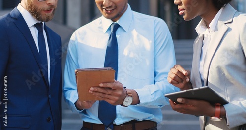Quadro su tela Multi ethnic males and female white-collars workers standing outdoors at street and watching something on tablet device