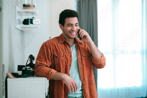 Happy young man enjoying phone talk with his friend