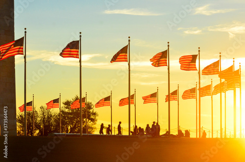 Washington Monument and silhouettes and waving national flags during sunset - Washington D.C. United States of America