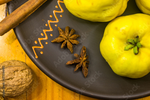 large yellow quince fruits on a ceramic plate, with anise, cinnamon, and walnuts