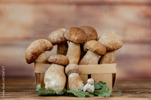 Basket of edible mushrooms: bolete and boletus, rustic wooden background, selective focus, toned image
