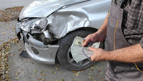 Damaged car inspection, male hands holding money, dollar banknotes, insurance agent or worker, mechanic