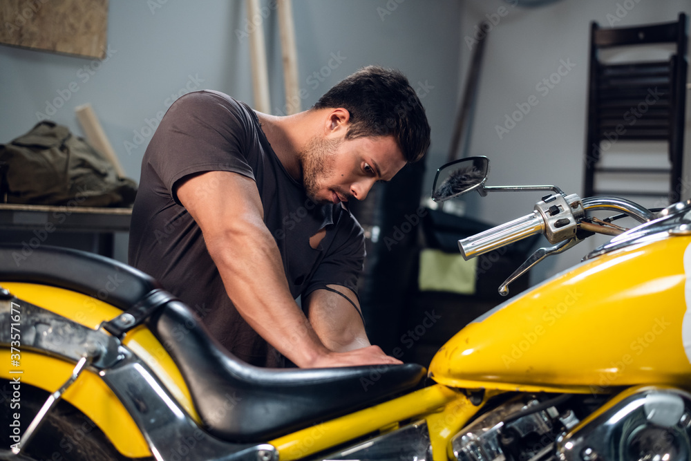A modern young man in a t-shirt and jeans is engaged in bike diagnostics in a repair shop or garage