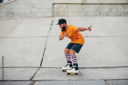 Handsome young stylish hipster guy with beard roller skating outdoors. Recreational activity. Aggressive roller skates
