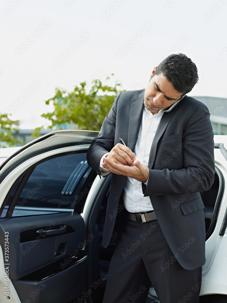 Businessman Takes Notes On Palm Of Hand During Phone Call Businessman Takes Notes On Palm Of Hand During Phone Call