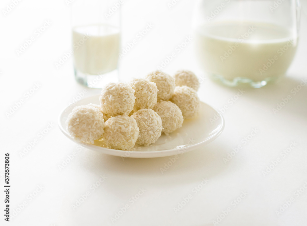 white chocolate coconut truffles on a plate against the backdrop of window shade. top view. white chocolate coconut truffles on a plate against the backdrop of window shade. top view.