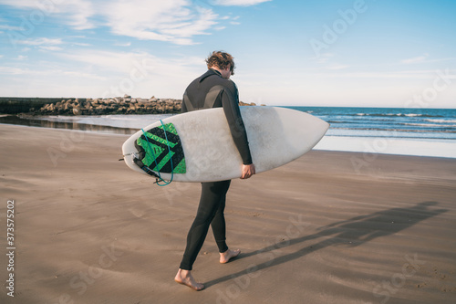 Surfer standing in the ocean with his surfboard.