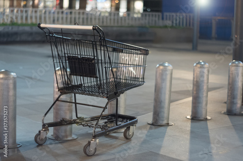 An empty shopping cart at the outside of the mall with light from spotlight.