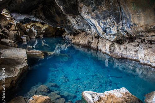 Natural Geothermal hot spring in the cave Grjotagja, Iceland blue water and colorful lava stones