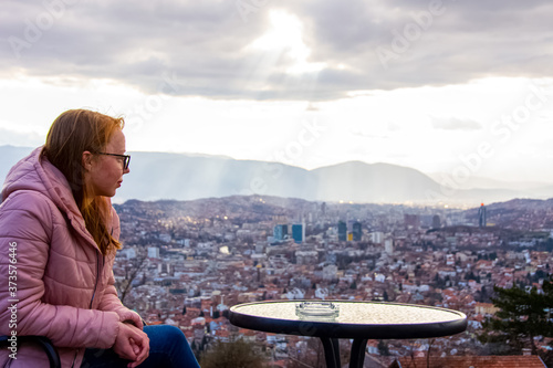 Woman sitting and drinking coffe above city of Sarajevo capital of Bosnia and Herzegovina photo