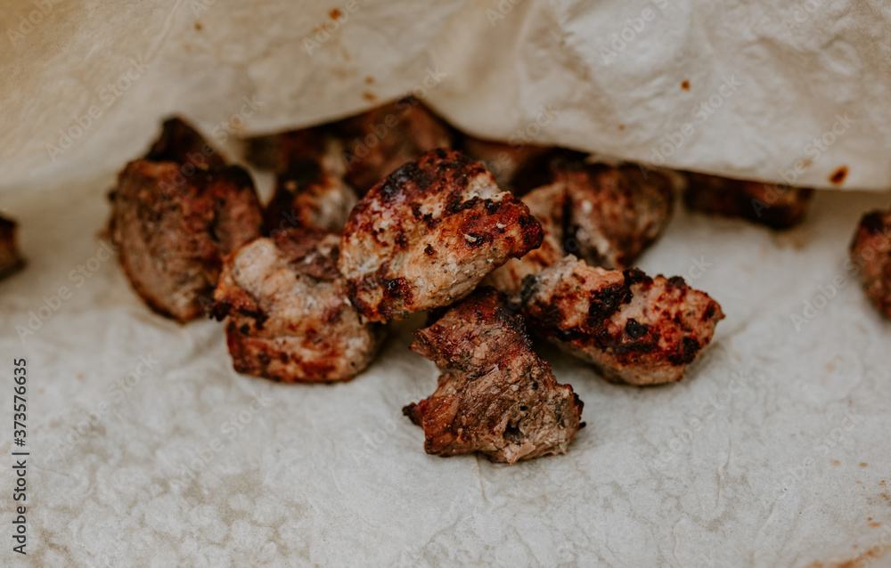Pork veal cow meat cut into square pieces and fried over a fire lies on a thin white pita bread. Pork veal cow meat cut into square pieces and fried over a fire lies on a thin white pita bread.