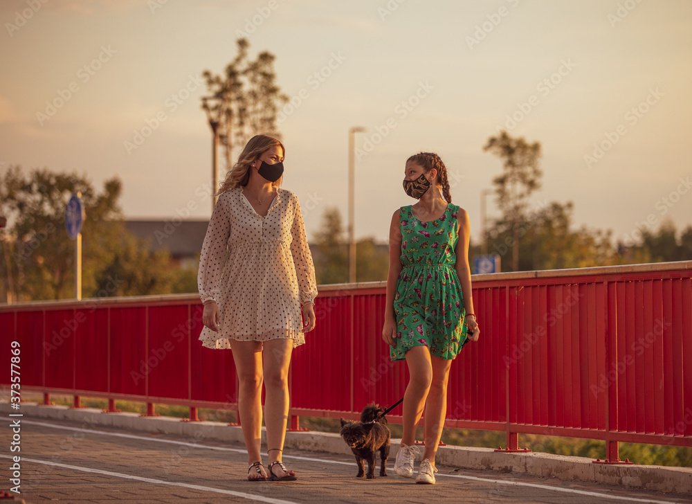 Naklejka premium Girlfriends walk the dog and wear face masks
