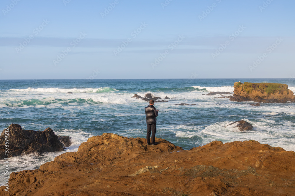 Man looking out over the Pacific Ocean, California coastline 