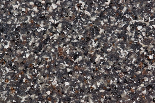 Black plastic with colored speckles throughout. Solid full frame abstract image for background and wallpaper. Close up macro view.