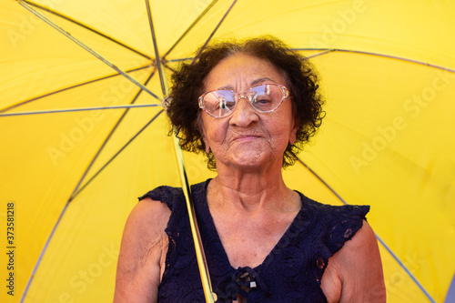 Close up elderly brazilian woman using a umbrella in the rain