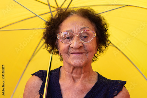 Close up elderly brazilian woman using a umbrella in the rain