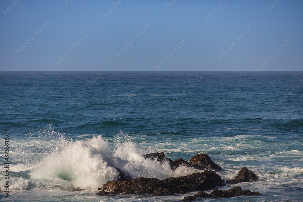 Waves breaking on large rocks in ocean
