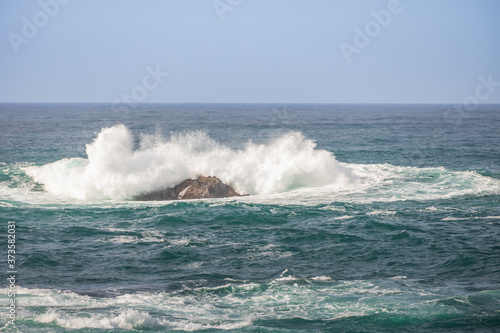 Waves breaking on large rock in ocean