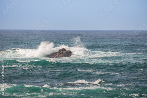 Waves breaking on large rock in ocean