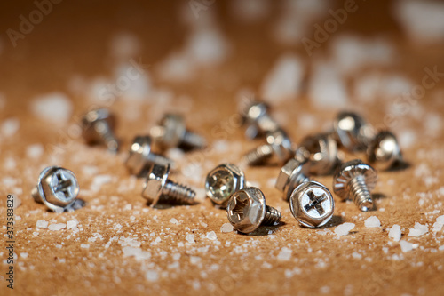 Metal screws on wooden table with salt stones