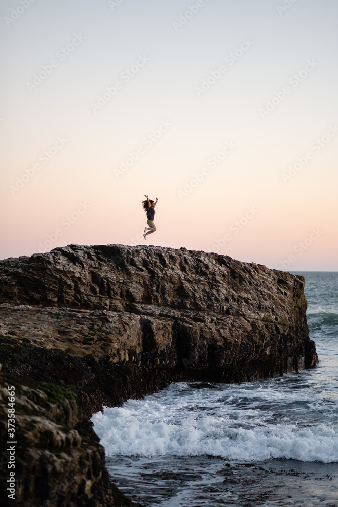 A Woman Jumping for Joy Enjoying the Ocean Views