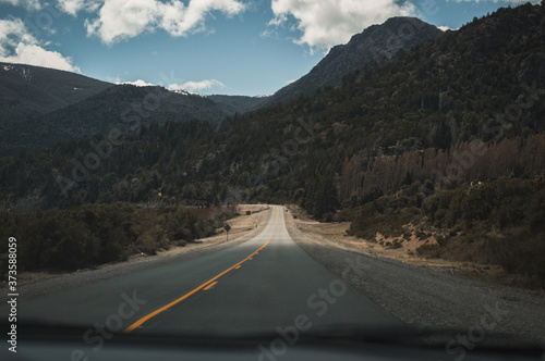 Ruta desde un auto con montañas de fondo.