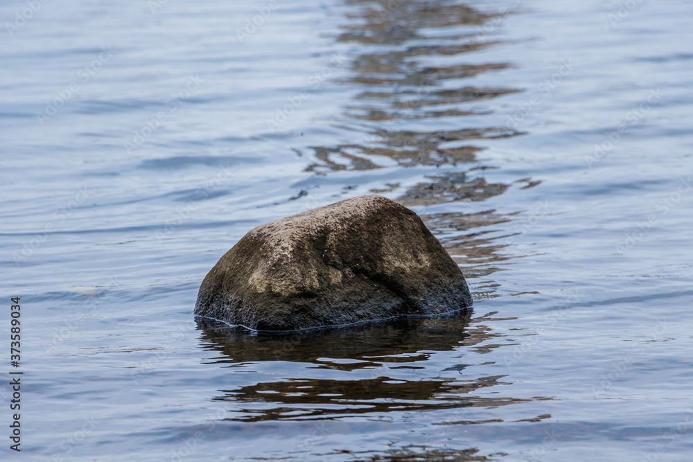 Fototapeta premium Lonely stones in dark water in lake