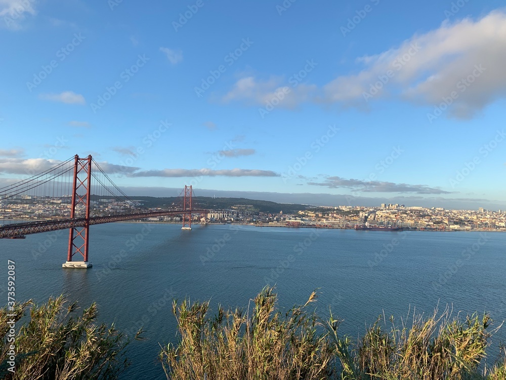 A statue of Cristo Rey and a view of the bridge named April 25 in Lisbon, Portugal. A statue of Cristo Rey and a view of the bridge named April 25 in Lisbon, Portugal.