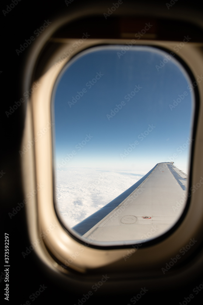 Naklejka premium Window from a plane in the sky with clouds below
