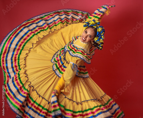 Bailarina vestida en traje tradicional folclórico mexicano amarillo en fondo rosa retrato photo