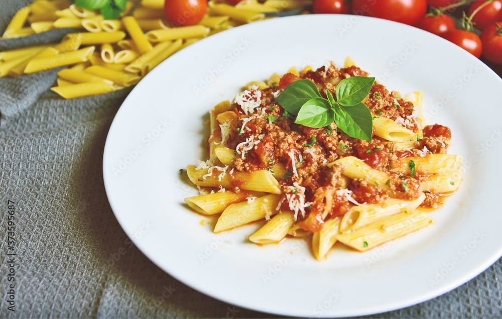 Penne bolognese with basil leaf on white plate. Penne bolognese with basil leaf on white plate.