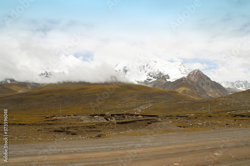 View of mountains with the snow on peak and dirt road in Tibet, China