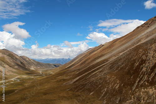 View of mountains and dirt road with the dramatic sky in Tibet, China