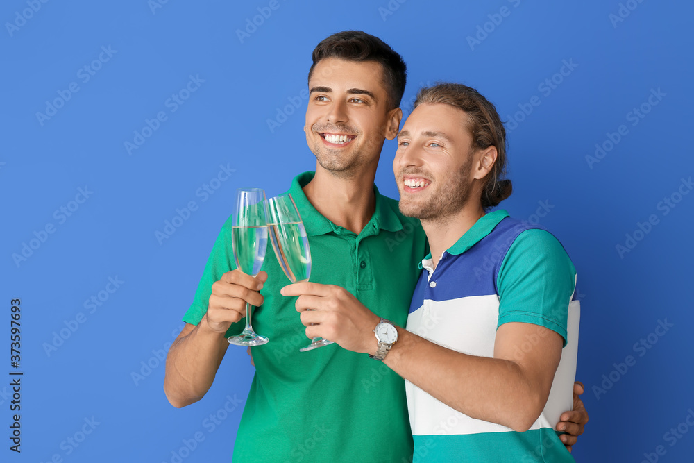 Happy gay couple with champagne on color background Happy gay couple with champagne on color background