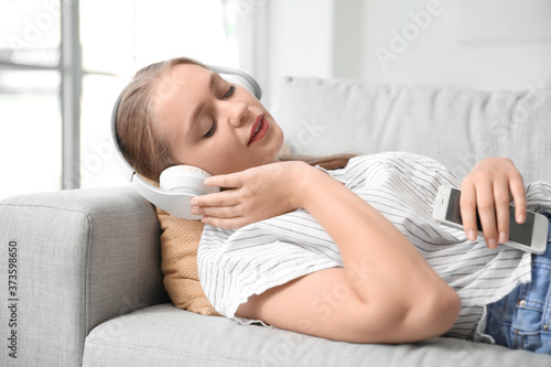 Sleepy young woman listenin...