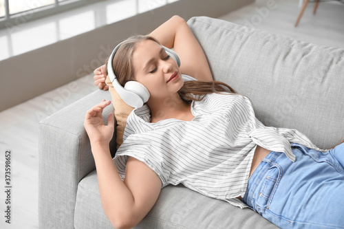 Sleepy young woman listenin...