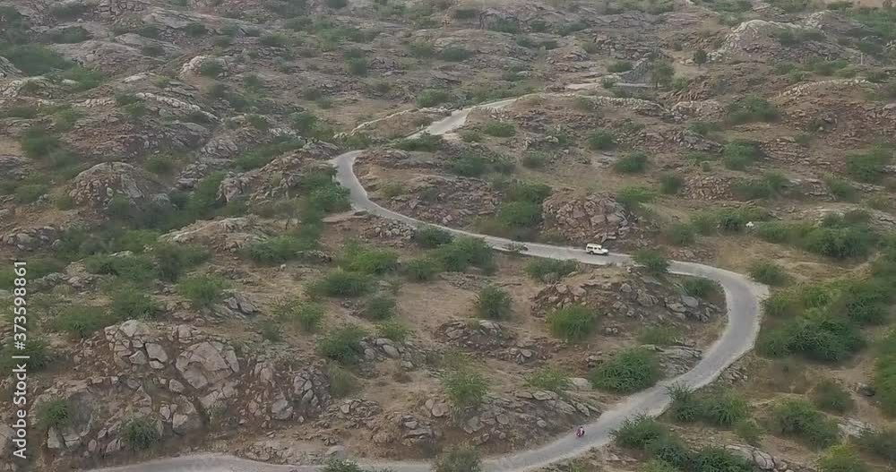 Cars Travelling On The Winding Road Surrounded By The Rocky Landscape In Pushkar, Rajasthan, India. - aerial drone Cars Travelling On The Winding Road Surrounded By The Rocky Landscape In Pushkar, Rajasthan, India. - aerial drone