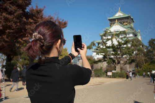 woman tourist taking a photo by smartphone at osaka castle japan