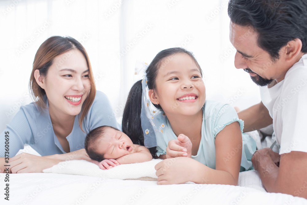 happy family mother, father and children laughing, playing and smiling in bed in bedroom at home. a young family with young children to bed in the bedroom.