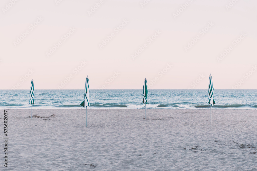 View of four closed beach umbrellas on the shore, Pinamar, Buenos Aires, Argentina.