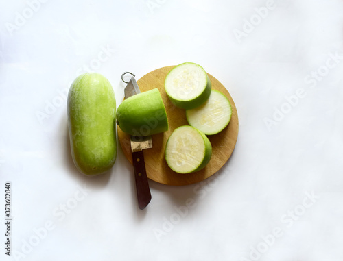 Fresh Green Winter Melon has been cut with a knife and a wood chopping block isolated on white background.