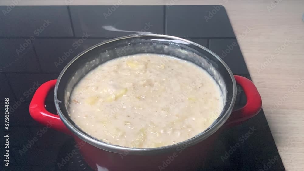 Bubbles coming out of a boiling oatmeal porridge with apples. Healthy meal from oats. Cooking oatmeal porridge in a black pot in slowmotion. Tasty and healthy oatmeal with apple for breakfast. Bubbles coming out of a boiling oatmeal porridge with apples. Healthy meal from oats. Cooking oatmeal porridge in a black pot in slowmotion. Tasty and healthy oatmeal with apple for breakfast.