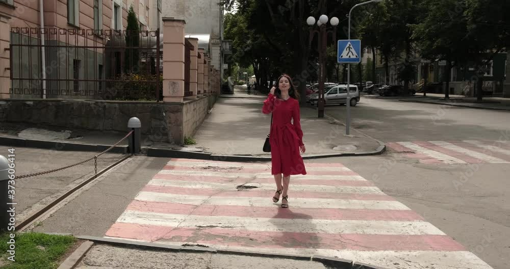 Cheerful young girl in red crosses the street Cheerful young girl in red crosses the street
