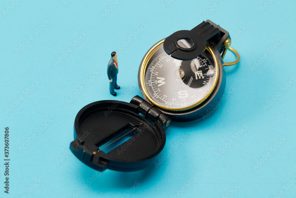 Miniature businessman and compass on blue background Miniature businessman and compass on blue background